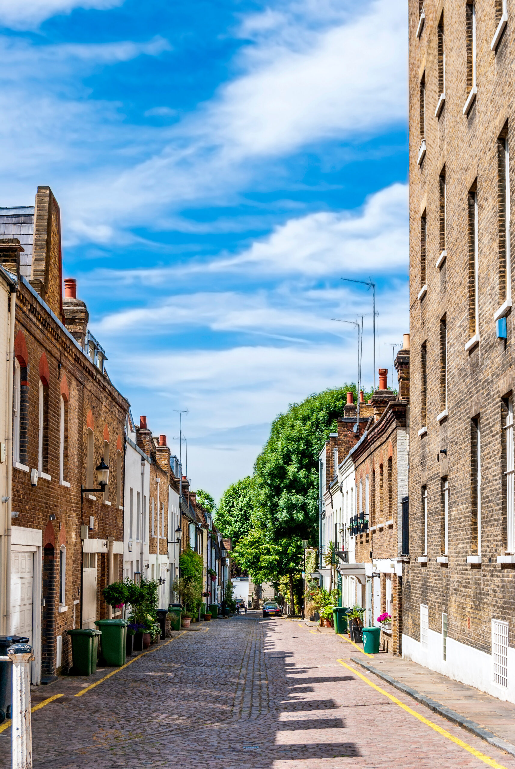 Residential street with red-brick houses and bushes of colorful flowers in Notting Hill area, west London, England, United Kingdom.